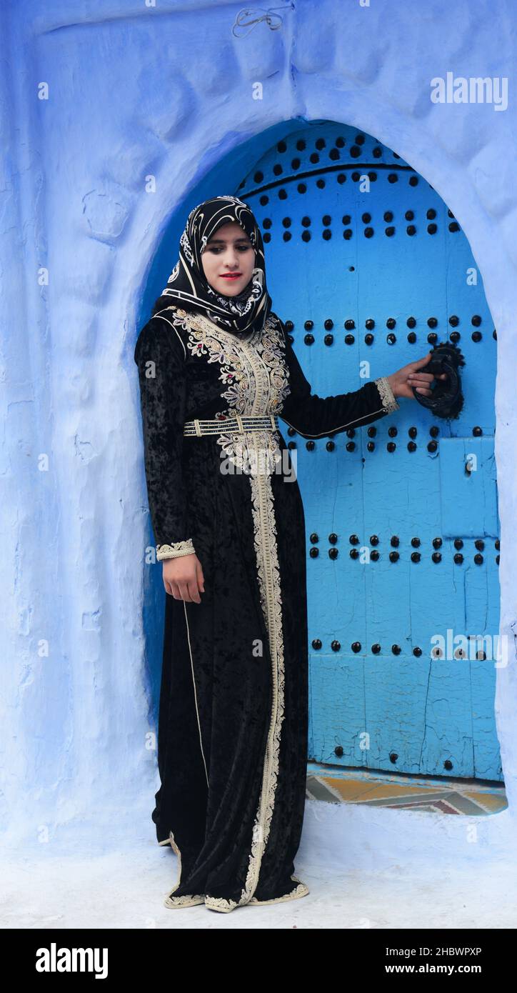 An Arab tourist posing by a traditional door in Chefchaouen, Morocco. Stock Photo