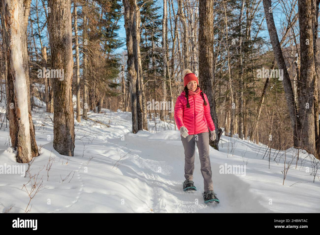 Winter snowshoe hiking people. Snowshoeing asian multiracial woman in winter forest on hike in snow wearing snowshoes living healthy active outdoor Stock Photo