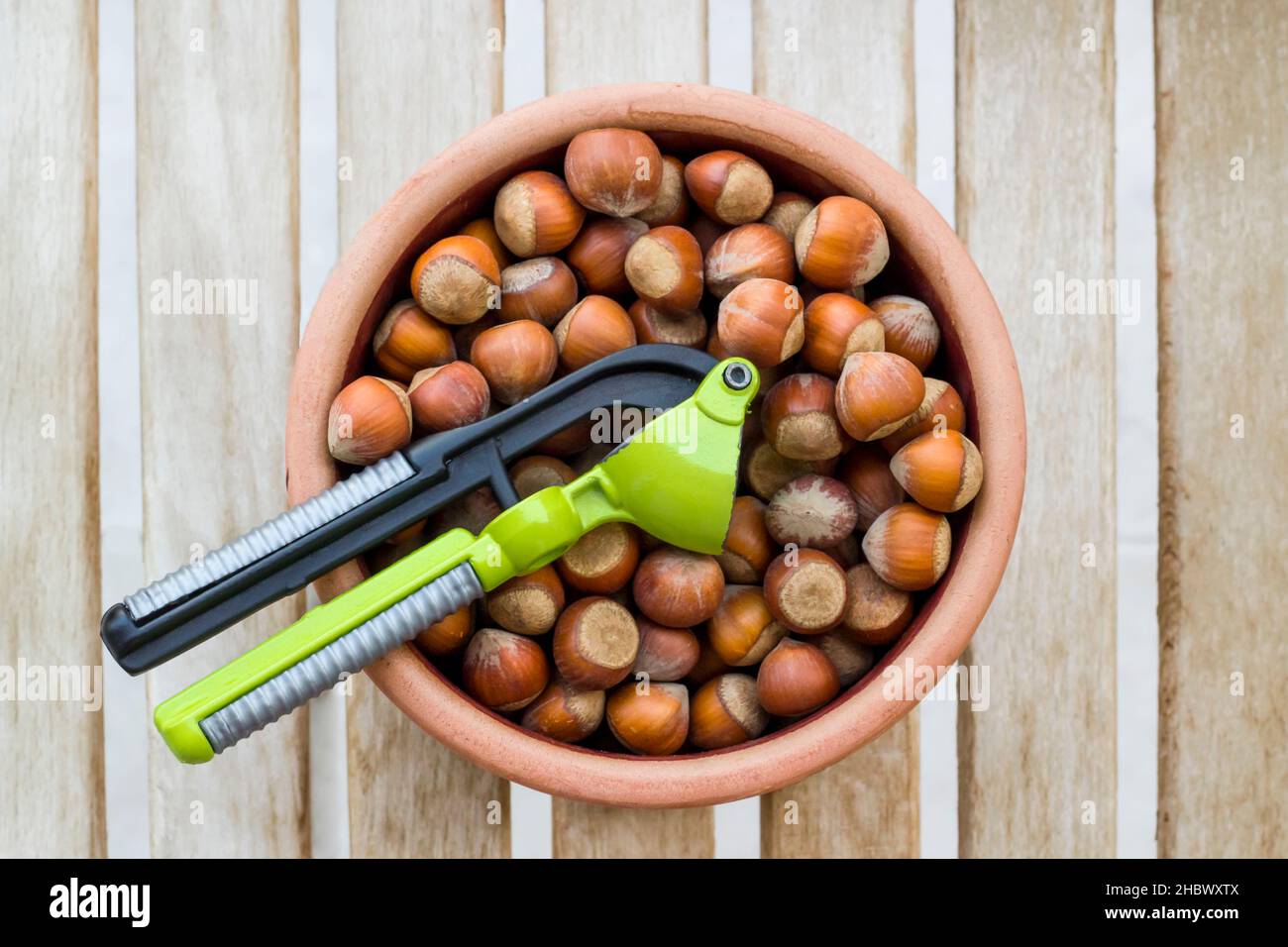 New crop hazelnuts in ceramic bowl with nut crusher on the wooden