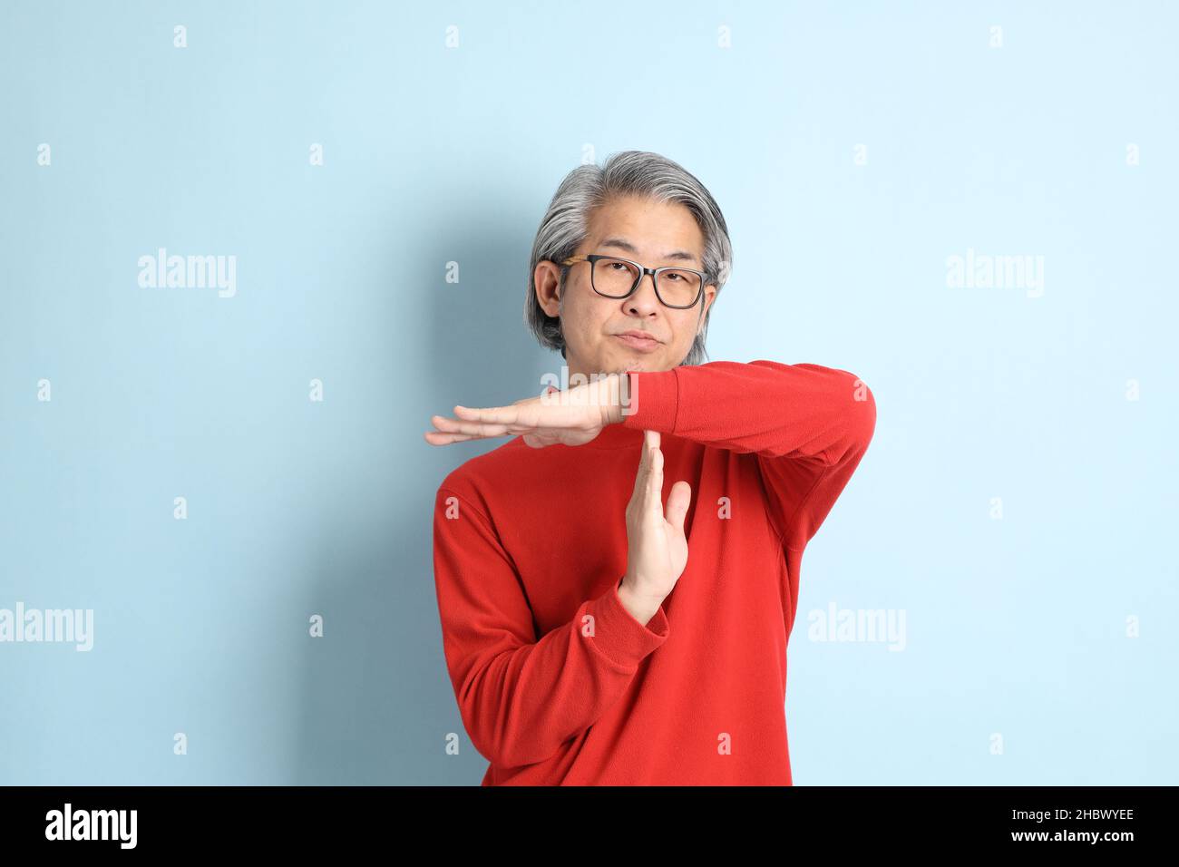 The senior Asian man standing on the blue background. Stock Photo