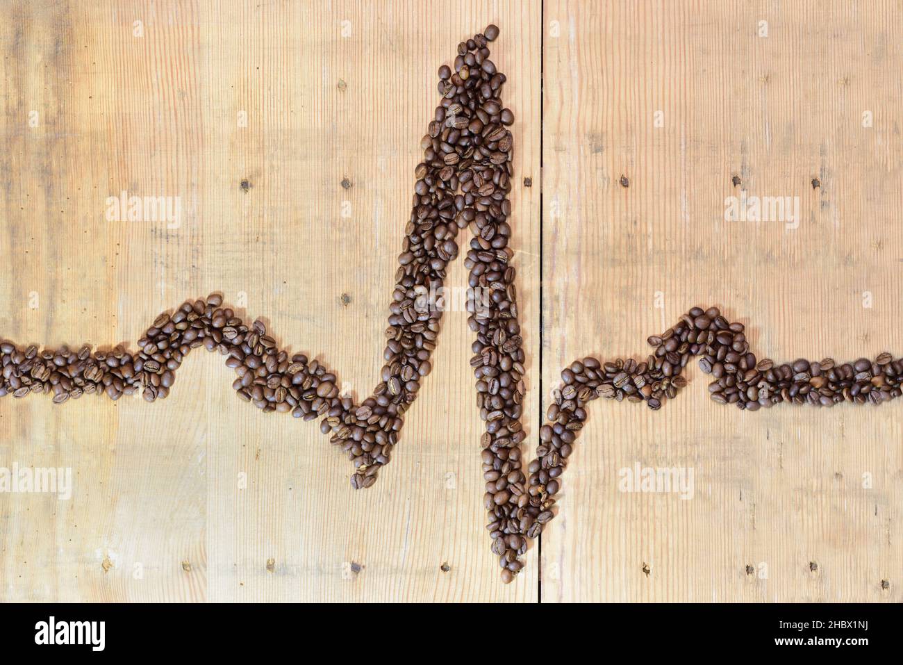 A QRS complex of the electrocardiogram was formed from roasted coffee beans on an old wooden board Stock Photo
