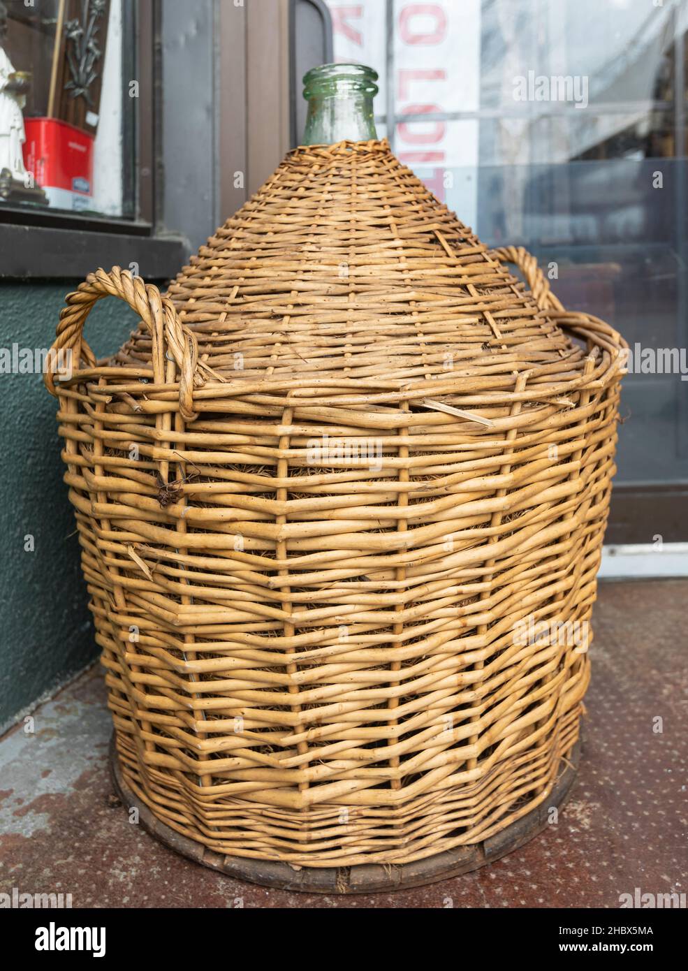 Vintage Wine Bottles in wicker basket on a barrel. Antique empty wicker