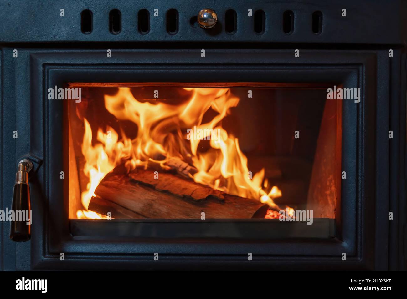 Stove fireplace and burning wood behind glass door, Black metal