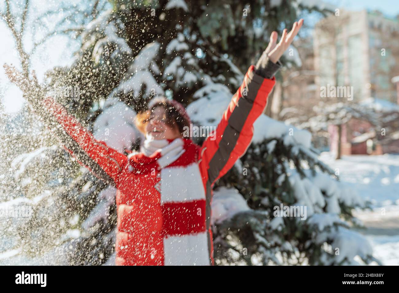 Positive teen girl loves winter, frosty snowy sunny day, snow. playing with snow, child throws white loose snow into air. forest walk Stock Photo