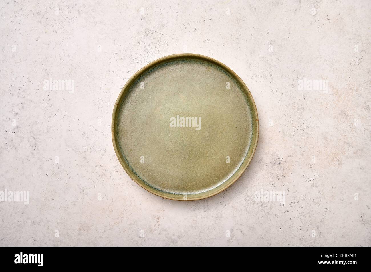 Empty green rustic ceramic plate on light textured marble background, flat lay, copy space Stock Photo