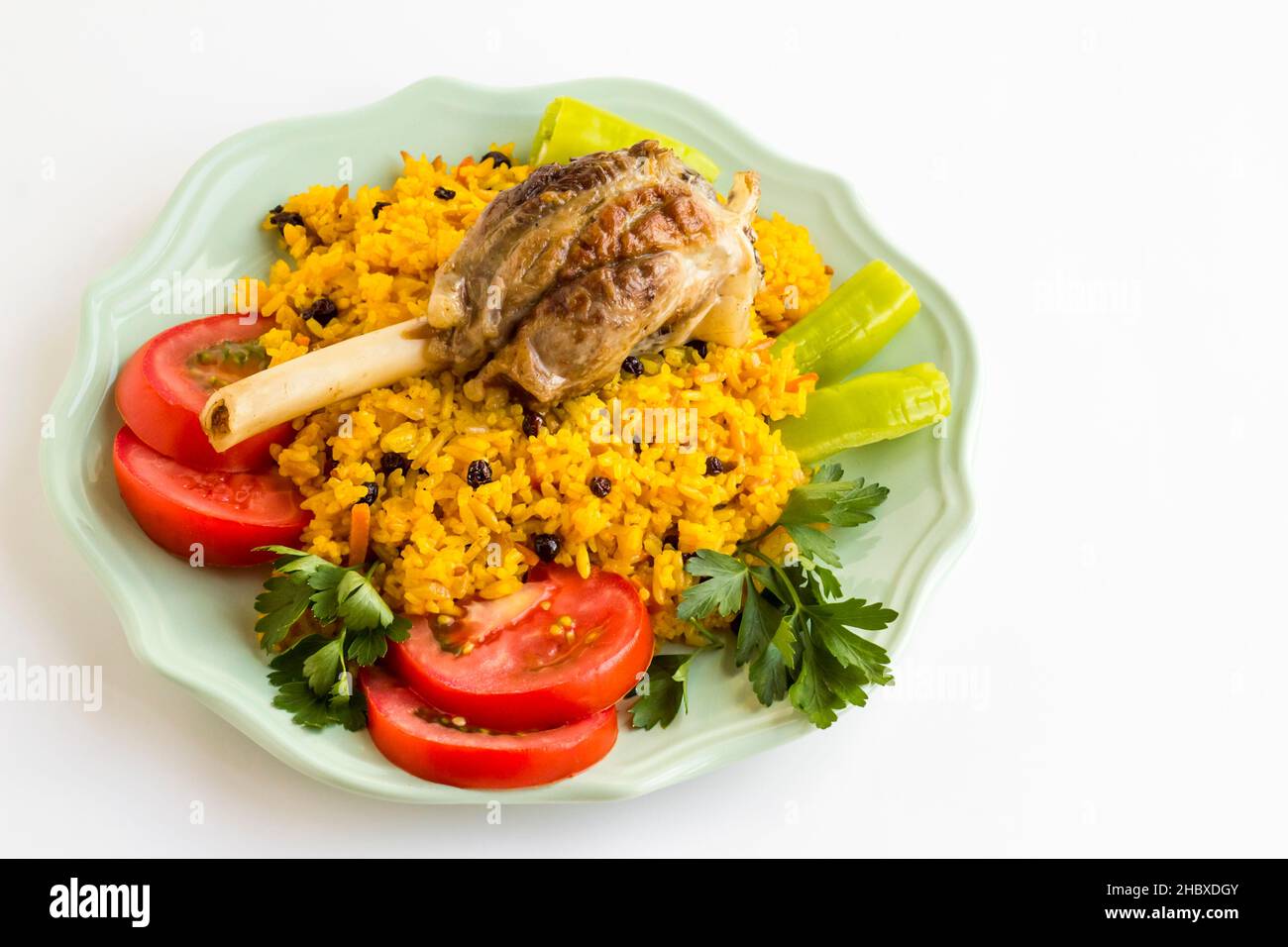 Traditional Arabic Rice,Pilaff with tomato,pepper,parsley and lamb shank in plate on white surface.Sacrifice Feast Concept Stock Photo