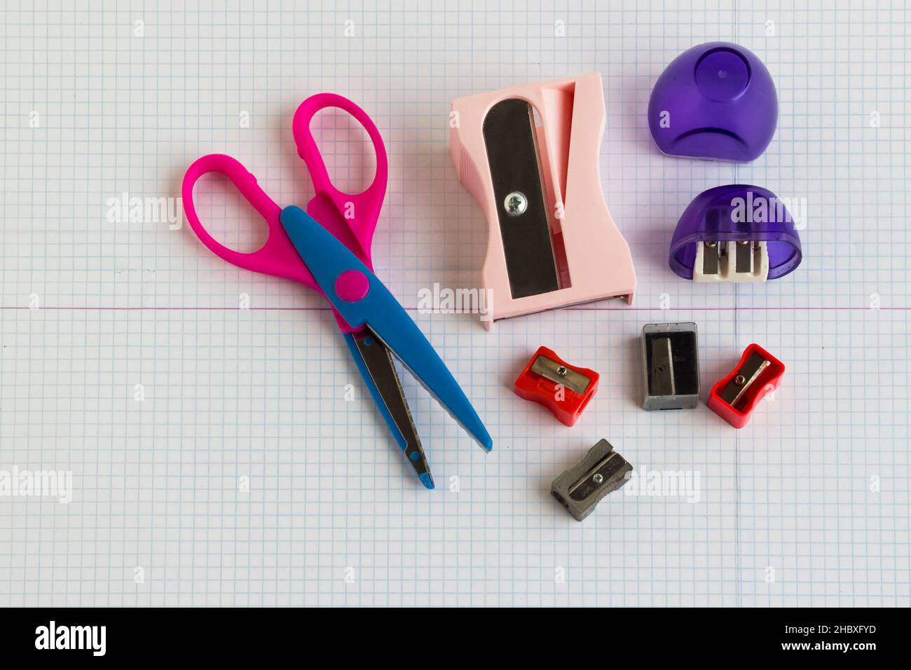 Assortment of sharpeners and a paper scissors on checkered paper Stock Photo