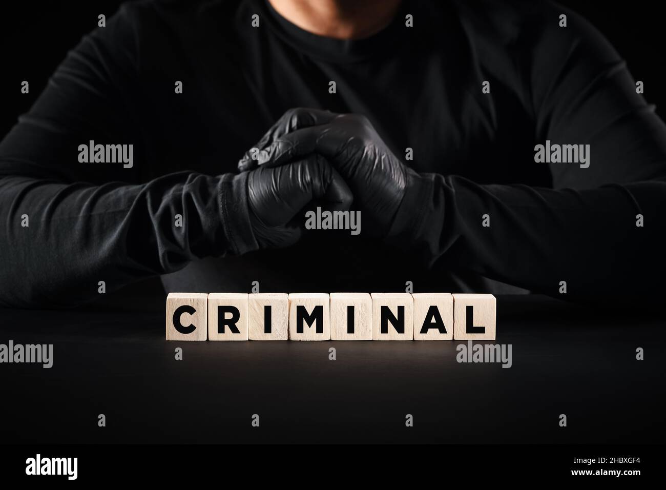 Crime, criminal, criminality, thief or burglar concept. The word criminal on wooden blocks with a criminal person background. Stock Photo