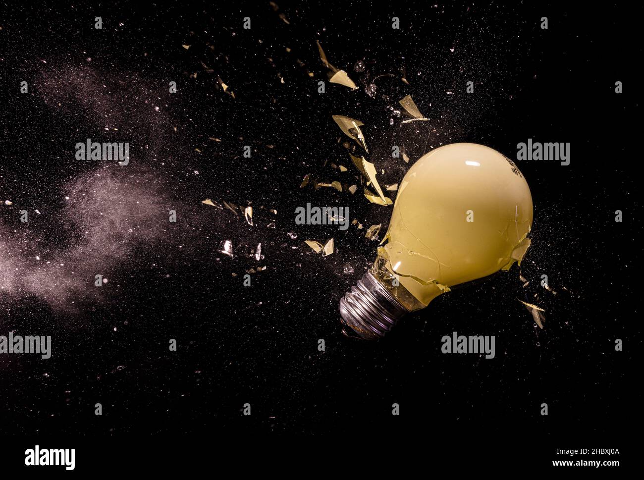 yellow light bulb breaking on black. Stock Photo
