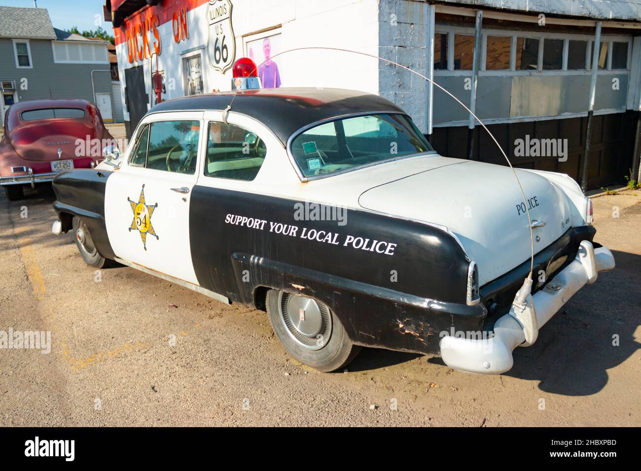 rear of vintage Plymouth police car parked outside the repair shop Dick