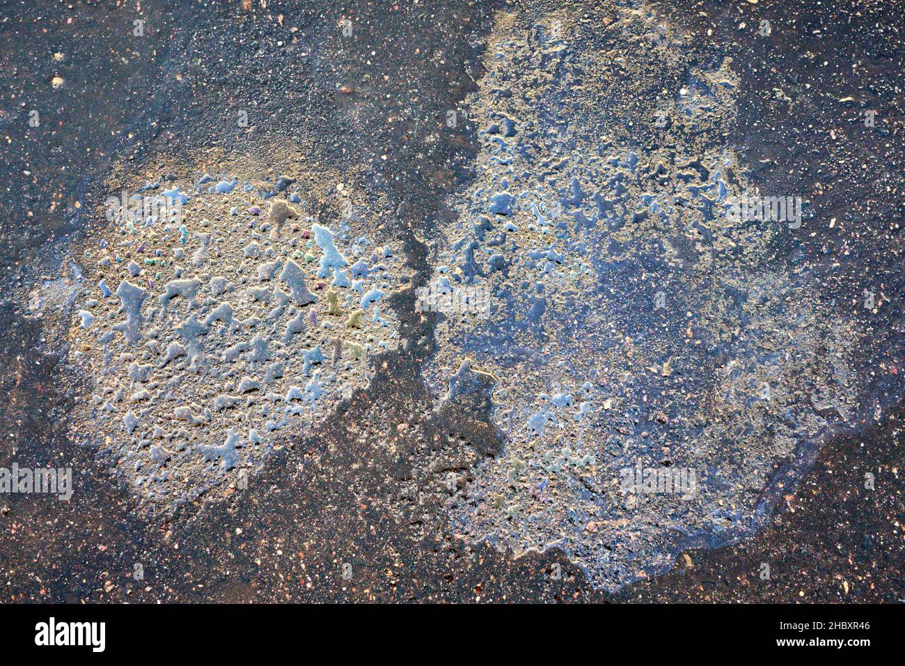Colorful gas stain on wet asphalt. Oil stain caused by a leak under a