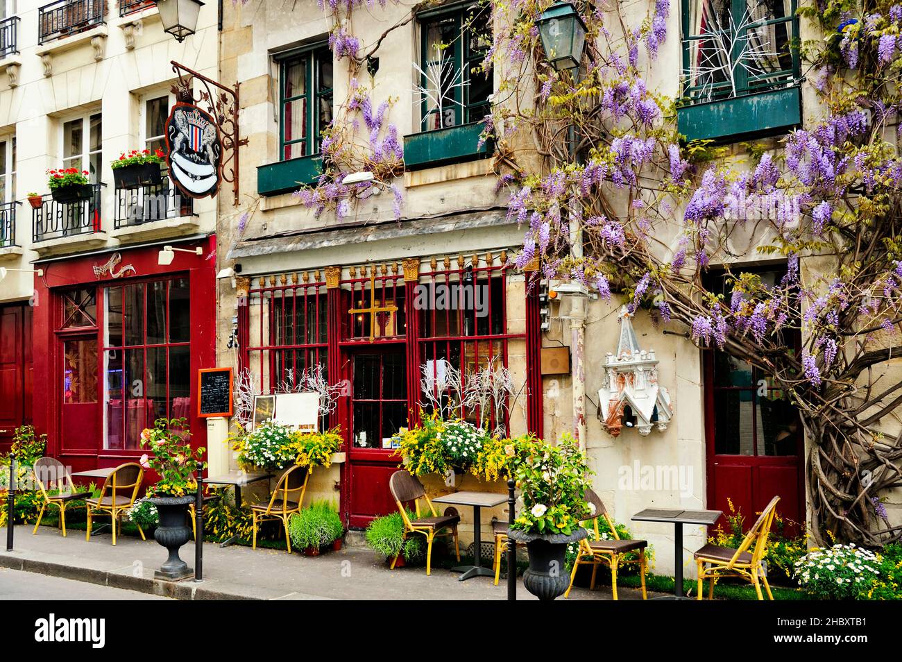 Cafe exterior, pavement exterior and flowering wisteria climbing plants, street signs. Stock Photo