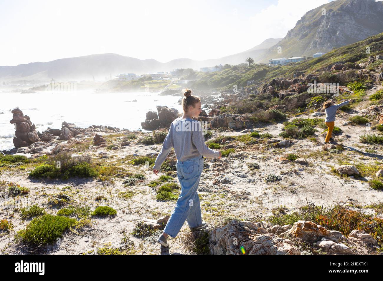 Teenage girl and a young boy walking along a coastal path above the ocean. Stock Photo