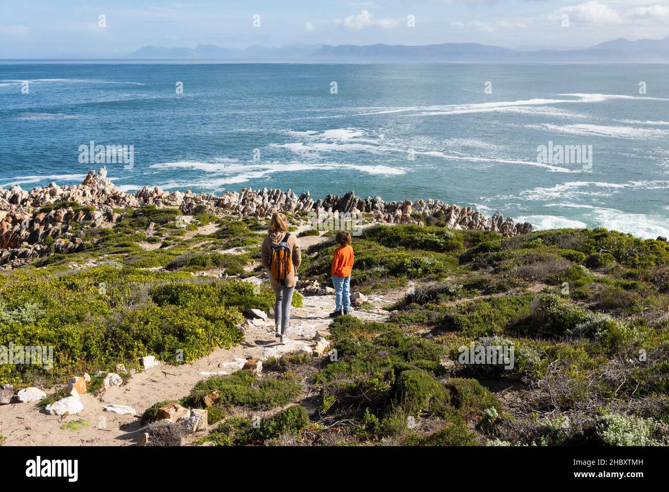 Two children walking along a coastal path to rock formations Stock Photo