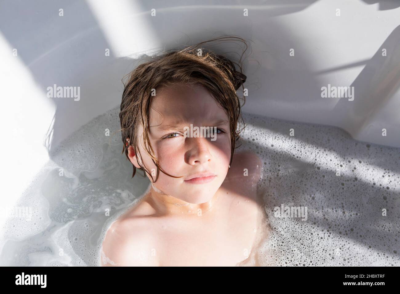 Eight year old boy in a bathtub, having a bath Stock Photo