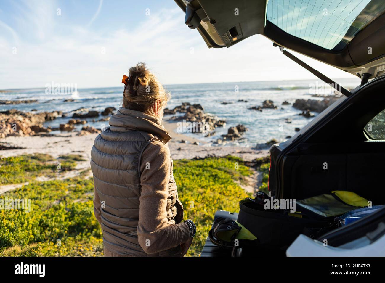 Adult woman by the open door of a vehicle at the beach getting ready for hiking. Stock Photo