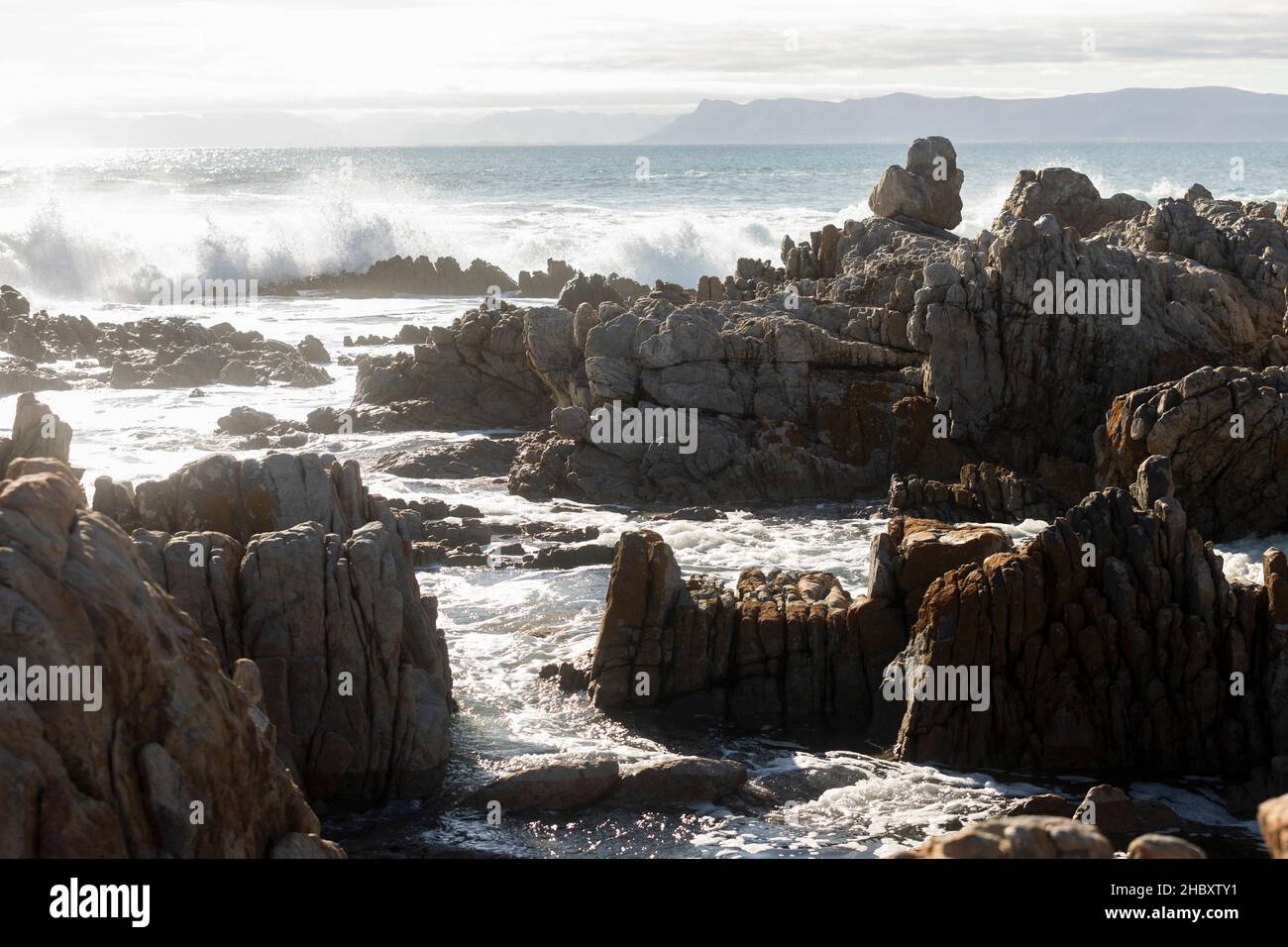 Jagged Tal Rocks Jagged rocks on the shore at De Kelders, tall waves rolling in and ...