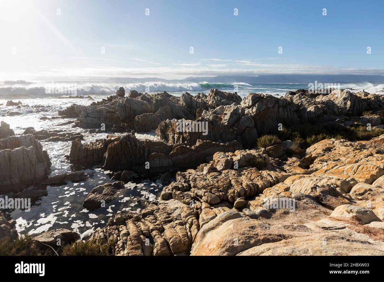 Jagged Tal Rocks Jagged rocks on the shore at De Kelders, tall waves rolling in and ...