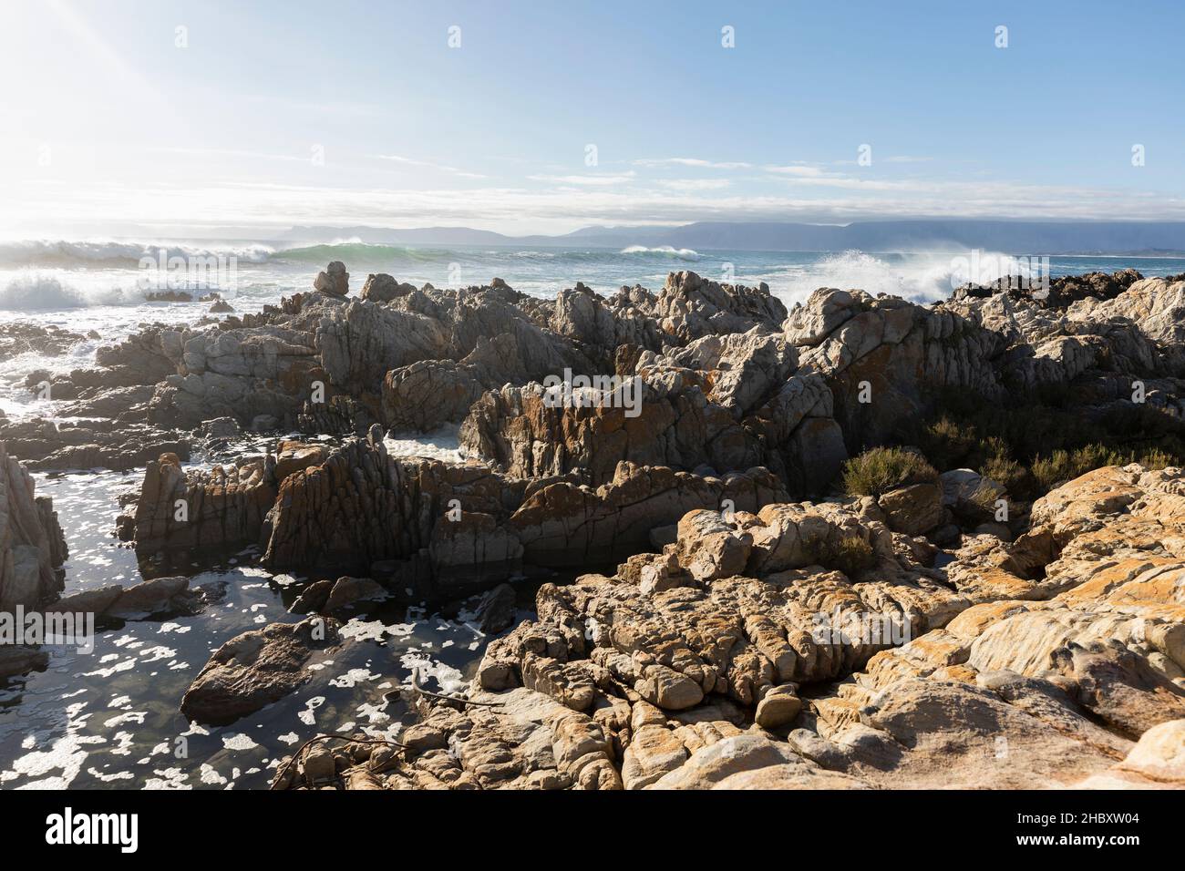 Jagged Tal Rocks Jagged rocks on the shore at De Kelders, tall waves rolling in and ...
