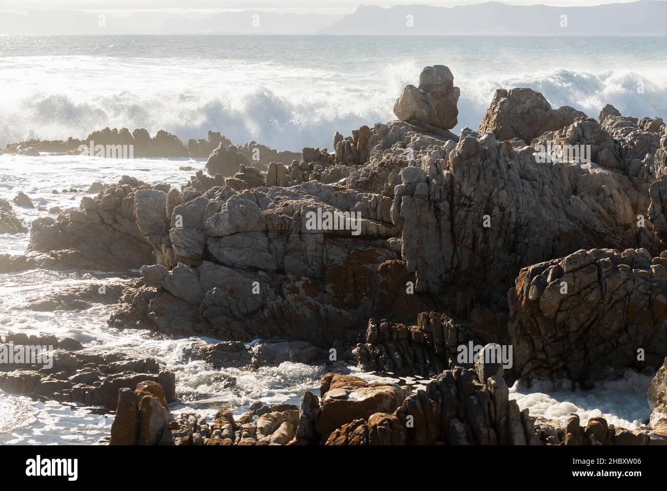 Jagged Tal Rocks Jagged rocks on the shore at De Kelders, tall waves rolling in and ...