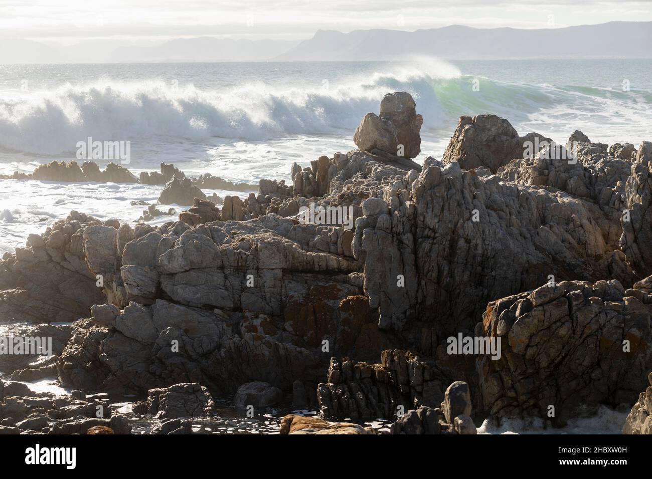 Jagged Tal Rocks Jagged rocks on the shore at De Kelders, tall waves rolling in and ...