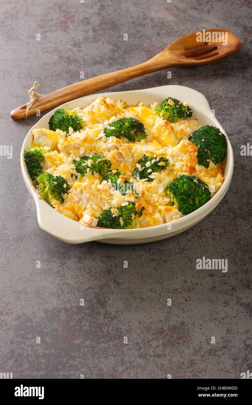 Chicken Divan is a creamy casserole that traditionally made with a chicken, broccoli, cream, cheese close up in the dish on the old table. vertical Stock Photo