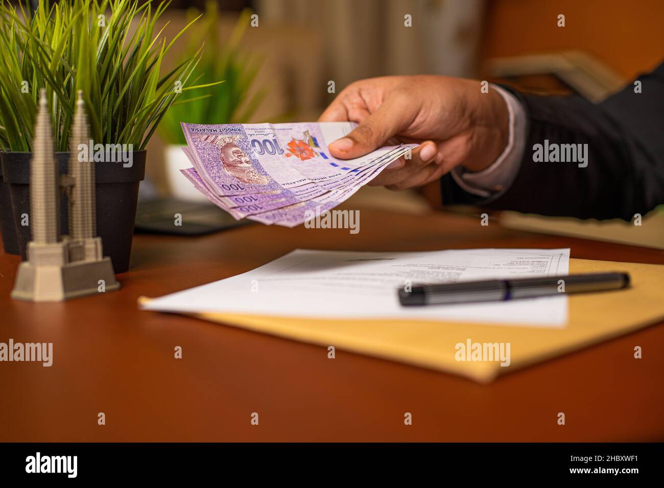 Corrupt Businessman or CEO or Politician hands giving bribe money after signing documents or contracts on an office desk. Venality, bribe, corruption Stock Photo