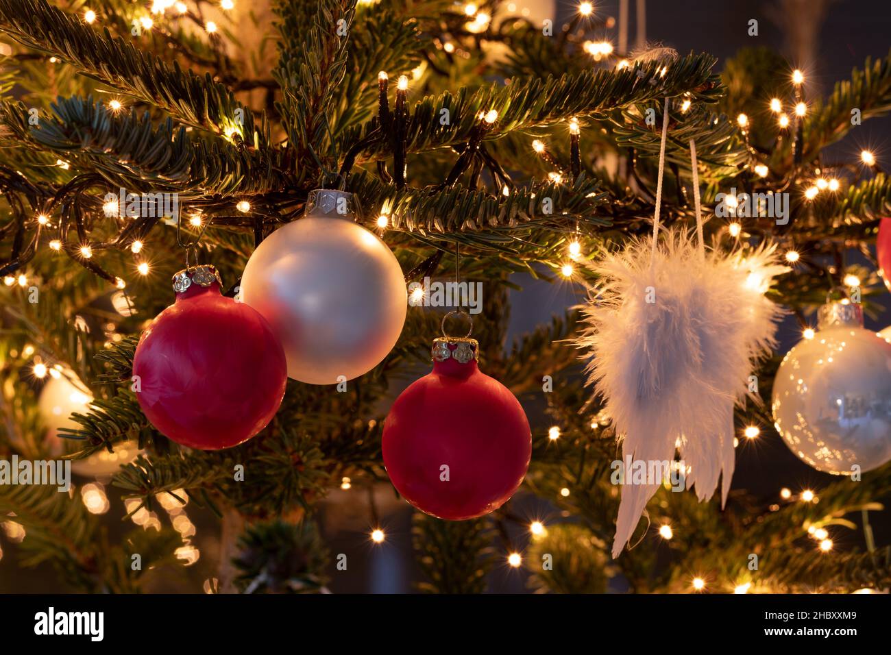 Christmas tree with red and white balls as well as a chain of lights and angel wings Stock Photo
