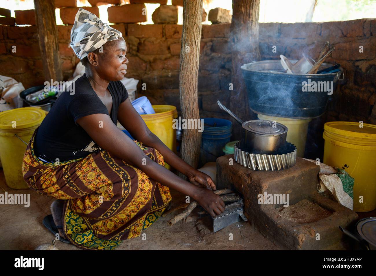 ZAMBIA, Sinazongwe, village Mweezya, woman cooks with energy saving firewood stove also called rocket stove / SAMBIA, Sinazongwe, Dorf Mweezya, Frau kocht mit Energiesparherd mit Feuerholz Stock Photo