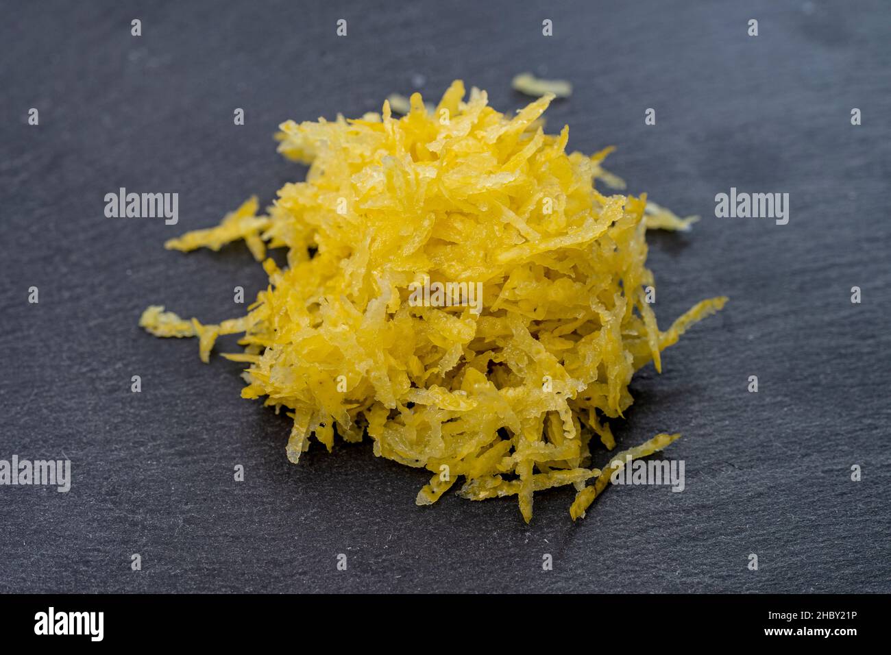 lemon zest isolated on black stone tile texture Stock Photo