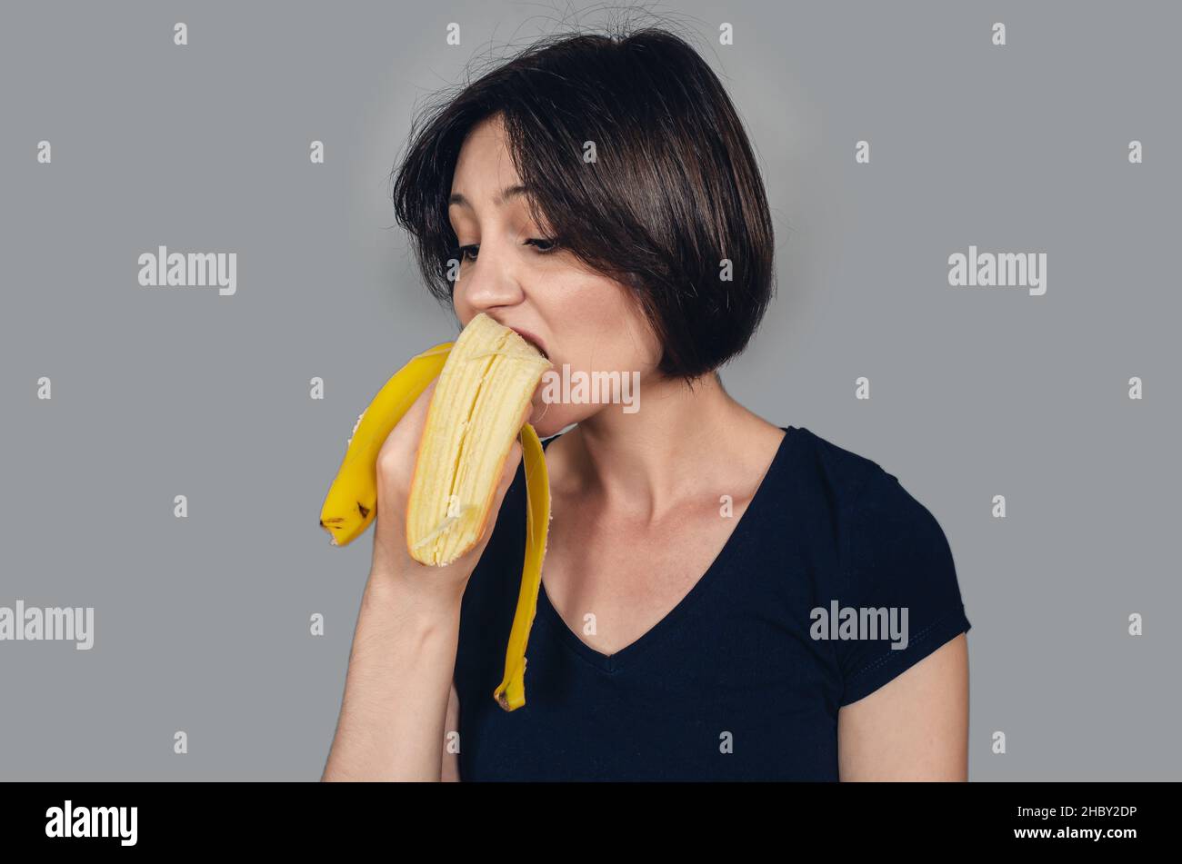 Beautiful darkhaired woman eating banana. Banana in awoman's mouth