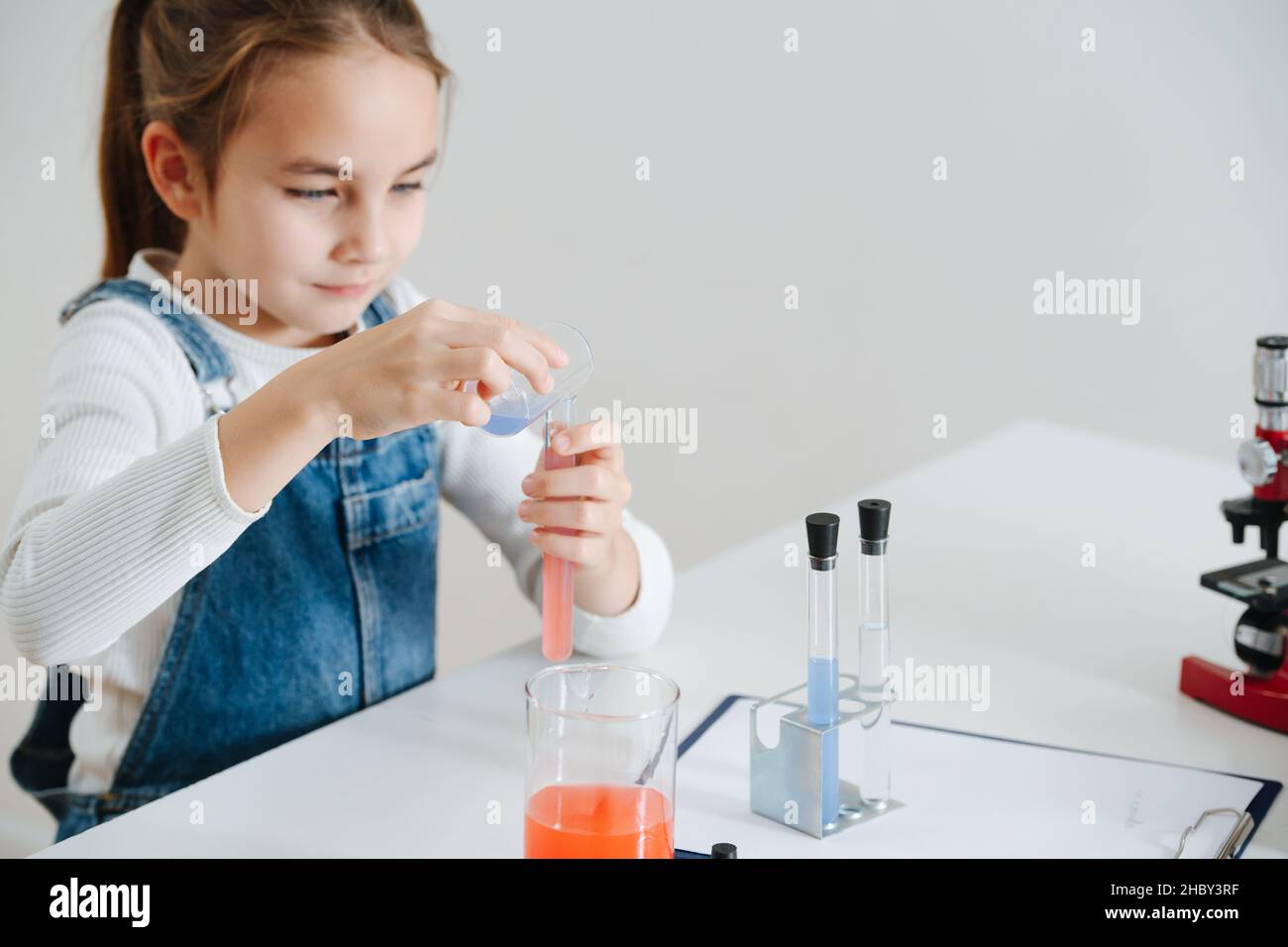 Patient little girl doing home science project, mixing red and blue
