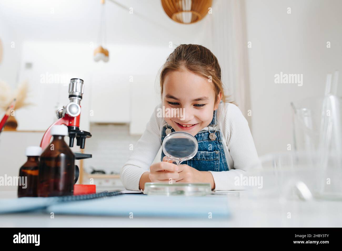 Amased little girl doing home science project, looking through ...