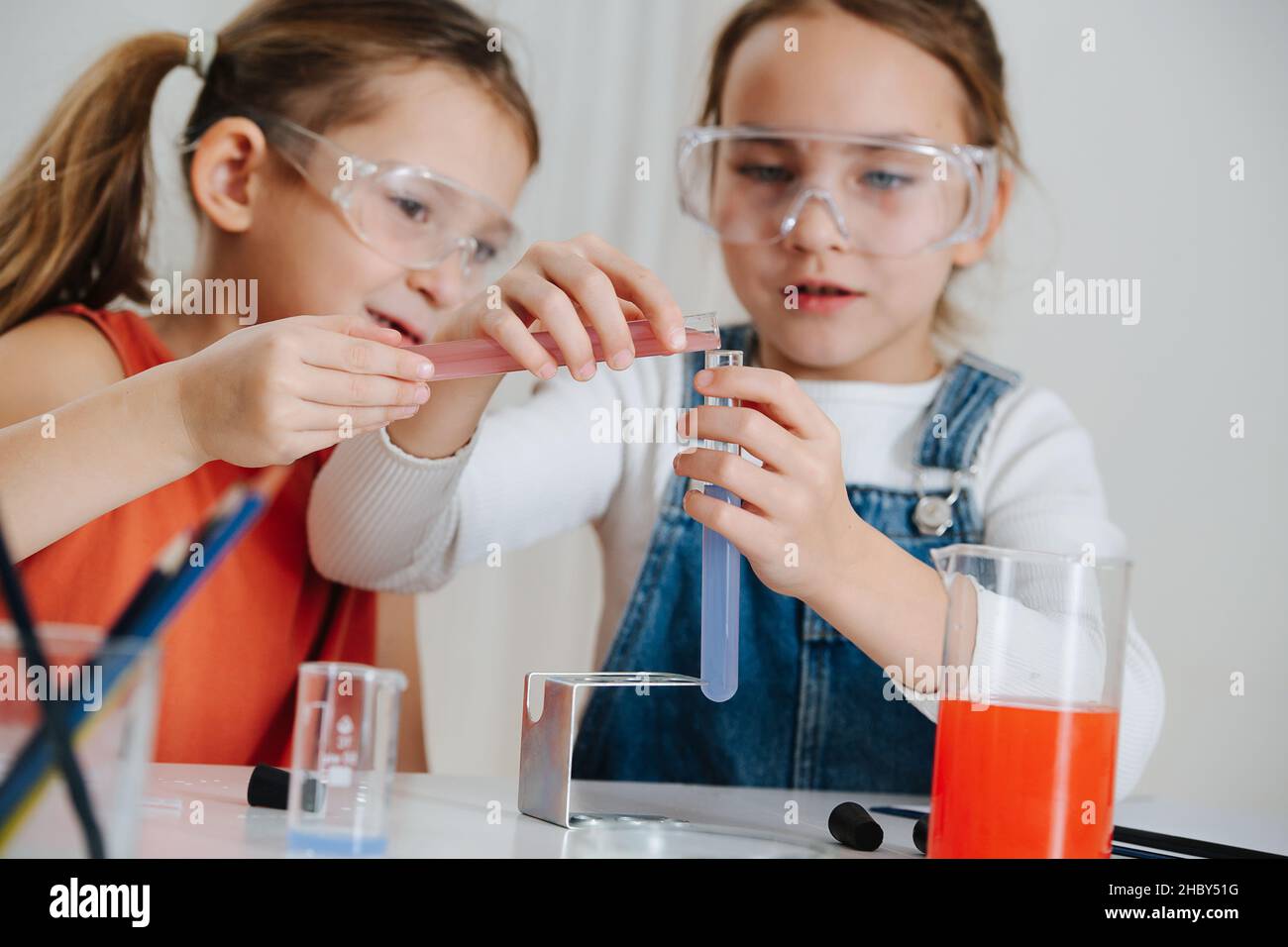 Happy little girls doing science project, they are mixing two colored liquids Stock Photo