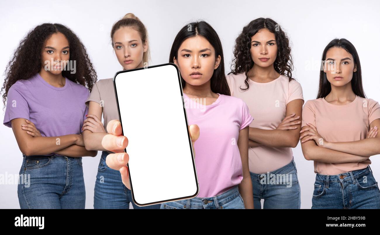 Serious ladies showing blank empty smartphone screen for mockup Stock Photo