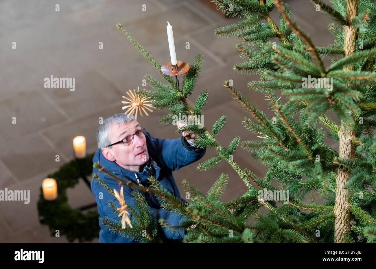 22 December 2021, Saxony, Meißen: Cathedral chaplain Stephan Kühne decorates the Christmas tree in the altar area of Meissen Cathedral on Albrechtsburg Castle. Construction of the Gothic church began at the end of the 13th century. Photo: Matthias Rietschel/dpa-Zentralbild/ZB Stock Photo