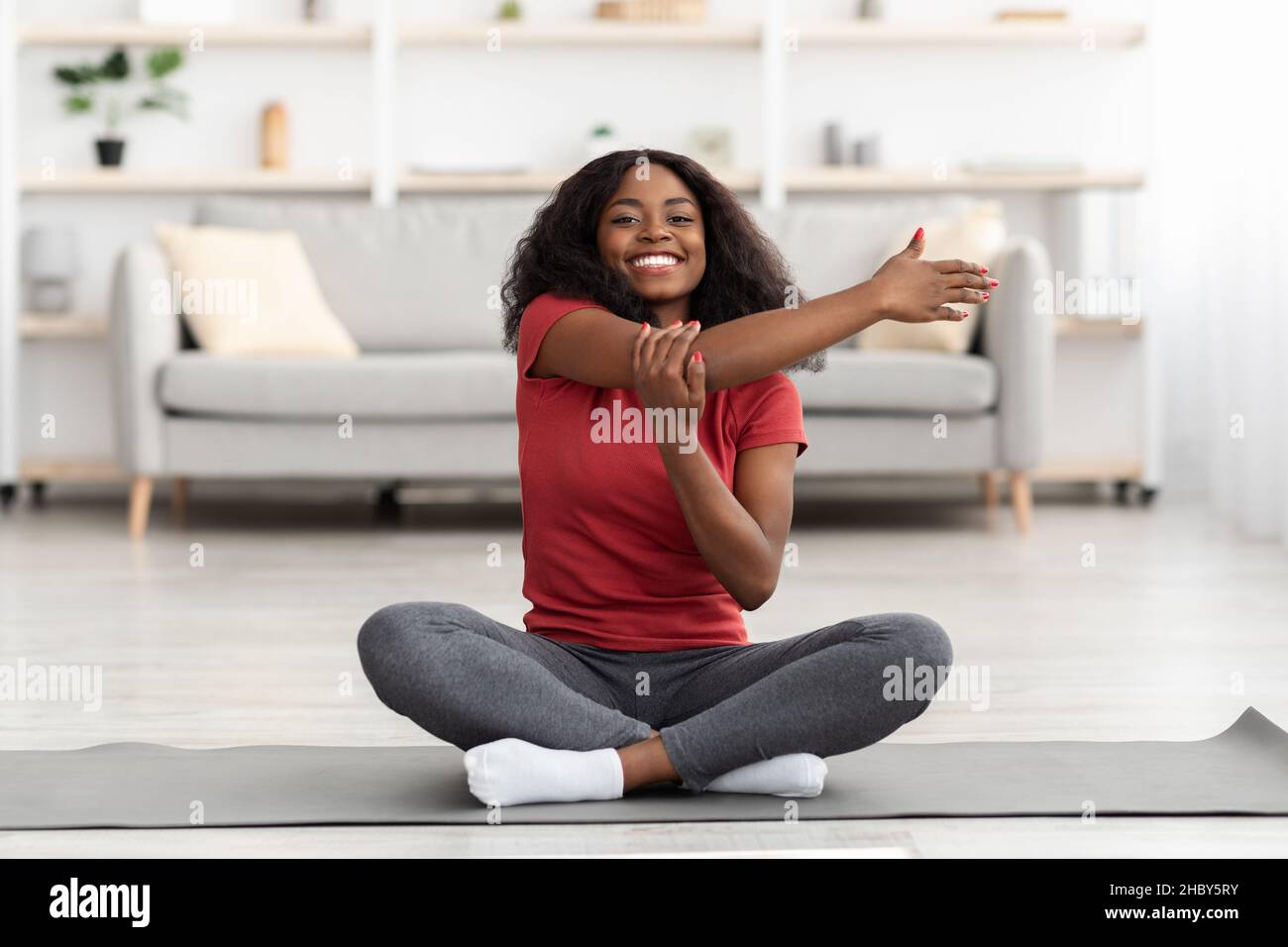 Happy athletic black woman stretching her body at home Stock Photo