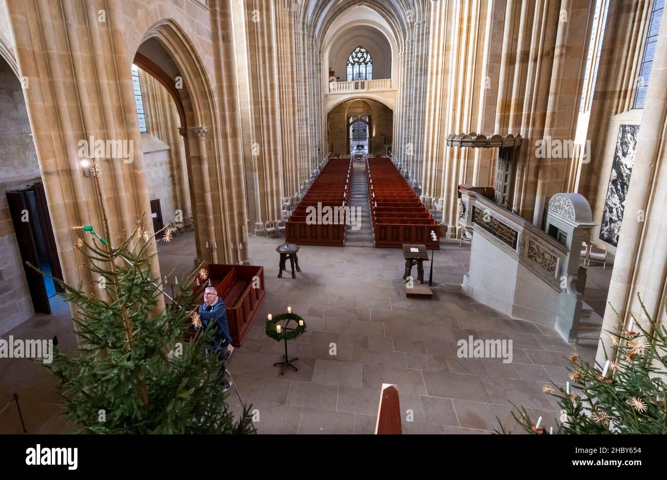 22 December 2021, Saxony, Meißen: Cathedral chaplain Stephan Kühne decorates the Christmas tree in the altar area of Meissen Cathedral on Albrechtsburg Castle. Construction of the Gothic church began at the end of the 13th century. Photo: Matthias Rietschel/dpa-Zentralbild/dpa Stock Photo