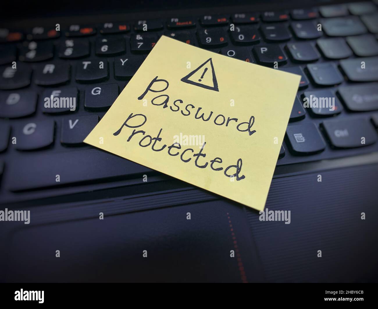 Password protected text written on sticky note on top of a laptop. Reminder to always secure your password from cyber hackers Stock Photo