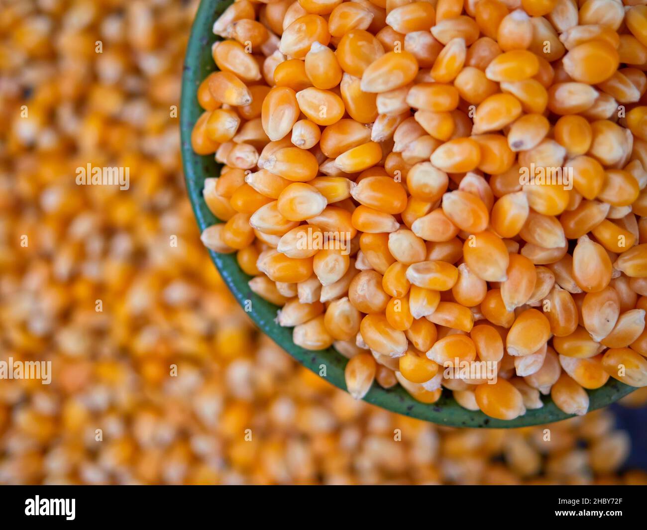 Popcorn kernels in a green bowl, top view, selective focus Stock Photo