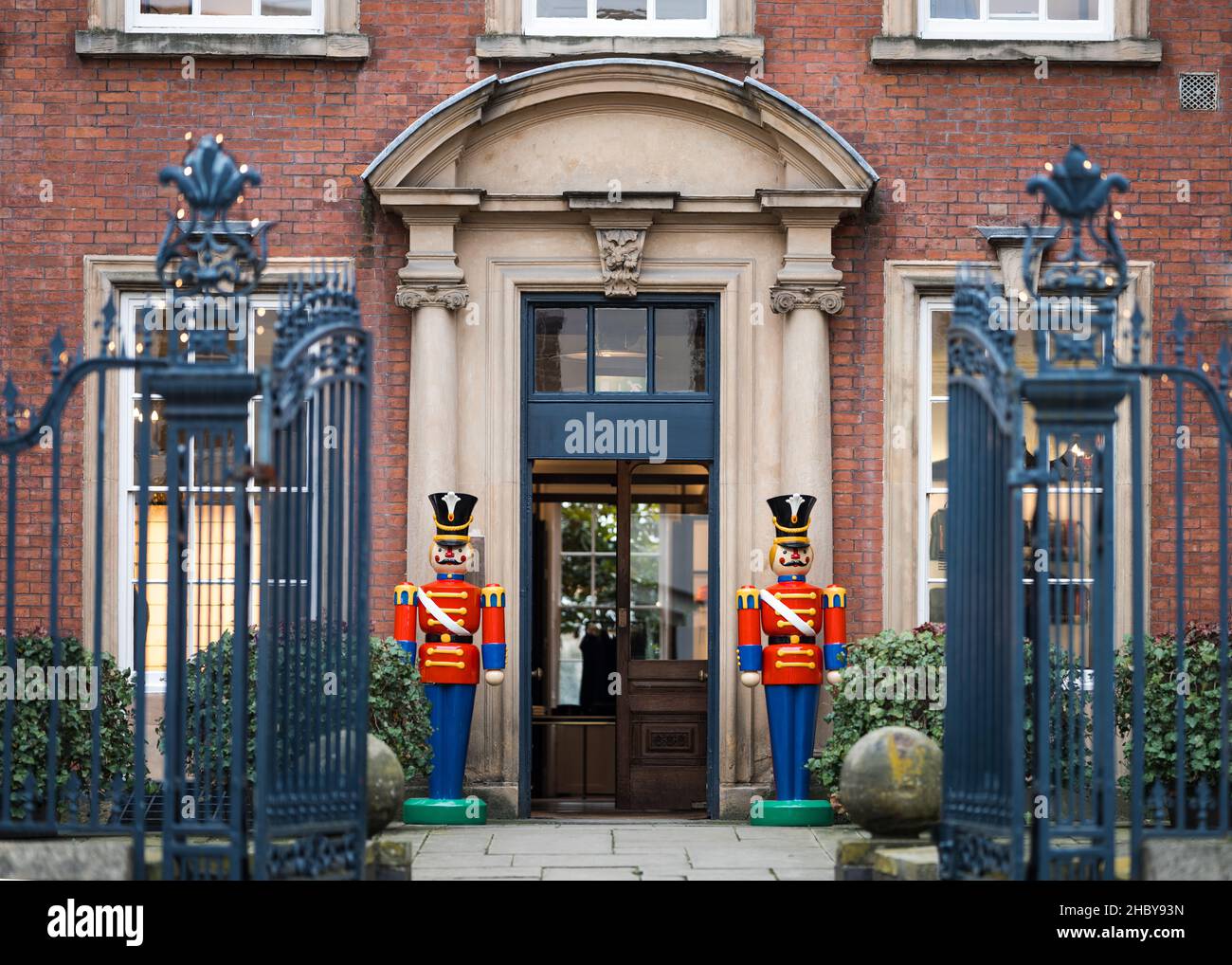 Bright coloured life size nut cracker Christmas decoration soldiers standing guard outside old building on shopping high street in red uniforms guard Stock Photo