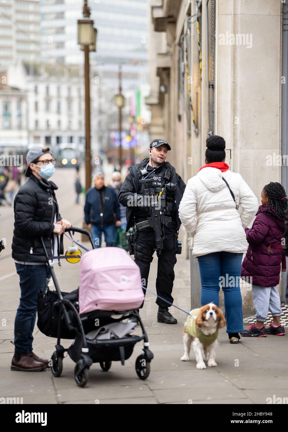 Armed response police force officer with firearms patrolling busy city street with public. Machine gun and pistol policeman in uniform holding weapon Stock Photo