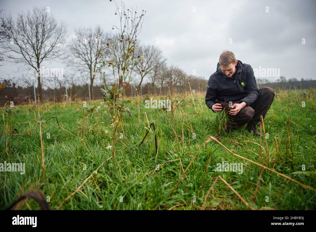 Kropp, Germany. 15th Dec, 2021. Hauke Sierck, farmer, looks at a piece of earth on a meadow of the family-owned farm Hof Fuhlreit. Credit: Gregor Fischer/dpa/Alamy Live News Stock Photo