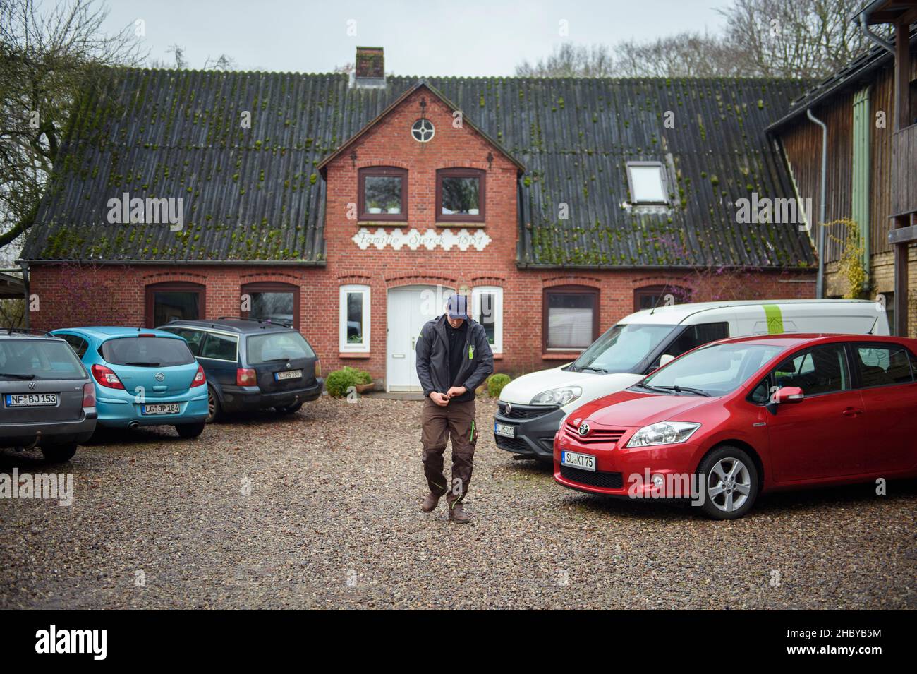 Kropp, Germany. 15th Dec, 2021. Hauke Sierck, farmer, walks over the family-owned farm Hof Fuhlreit while putting on a jacket. Credit: Gregor Fischer/dpa/Alamy Live News Stock Photo