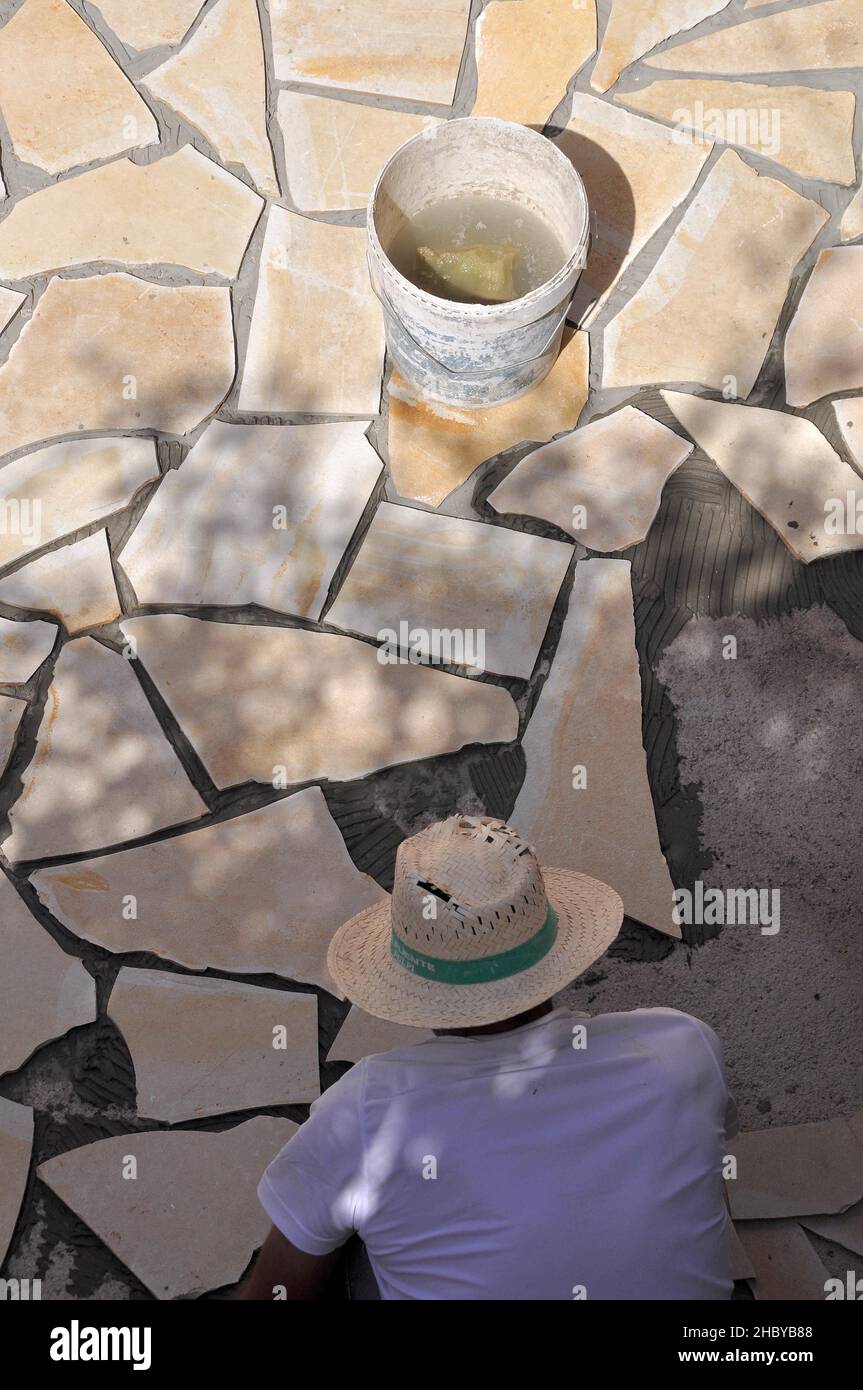 Worker laying natural stone tiles, laying floor tiles of a inner