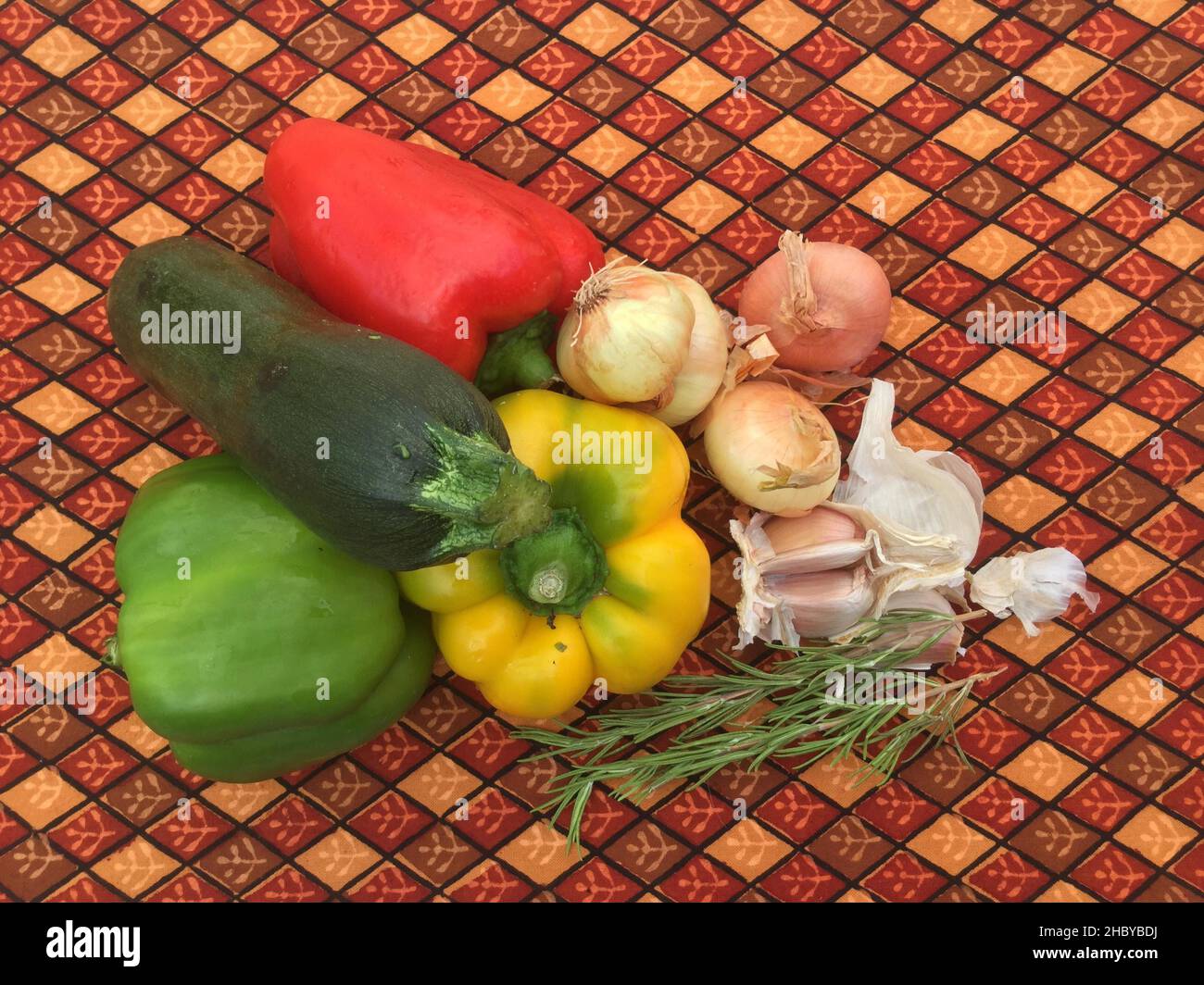 Red and green peppers, courgettes, onions and garlic with rosemary on