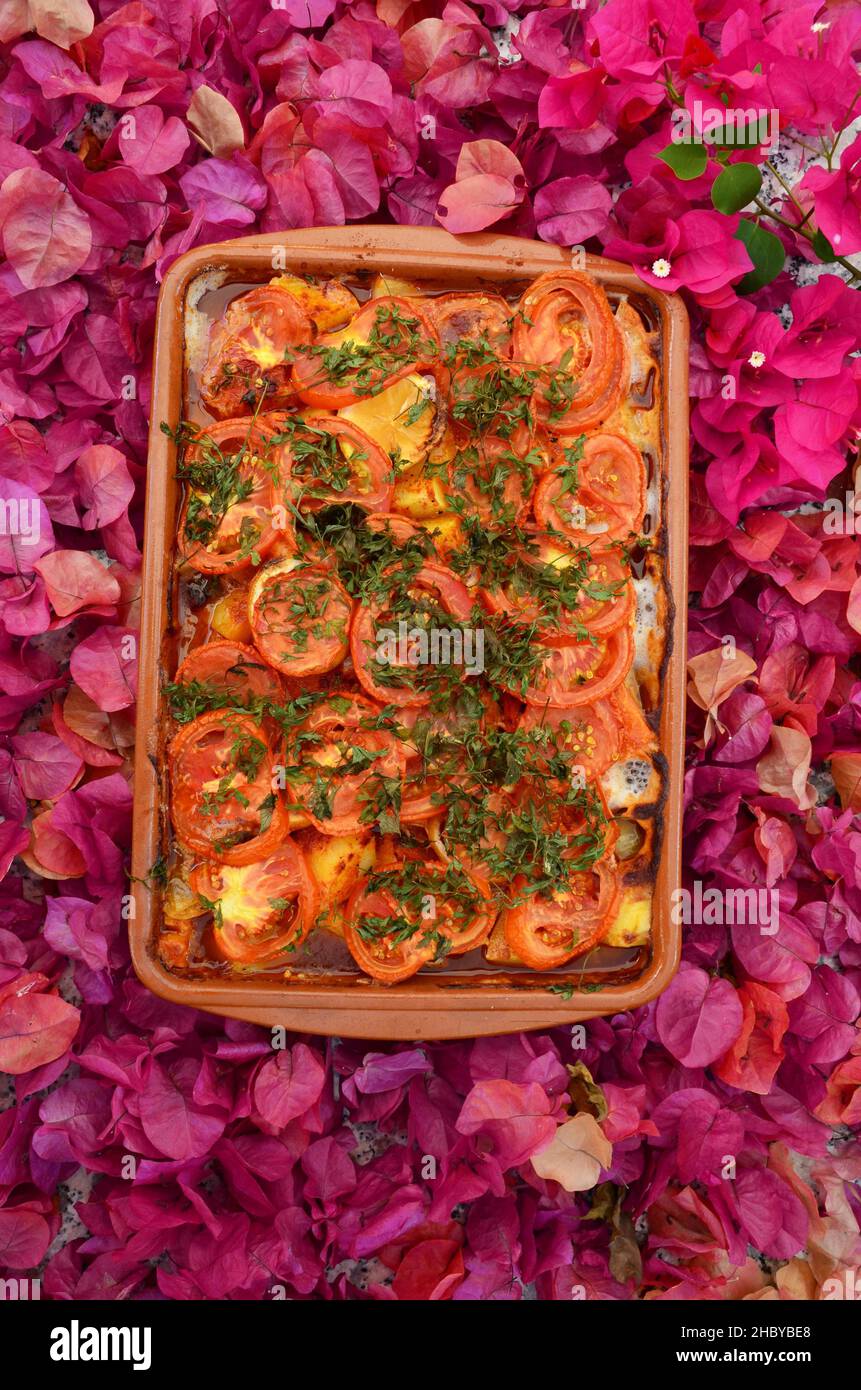 Clay pot with tomatoes in bed on leaves of bougainvilea, top view, from