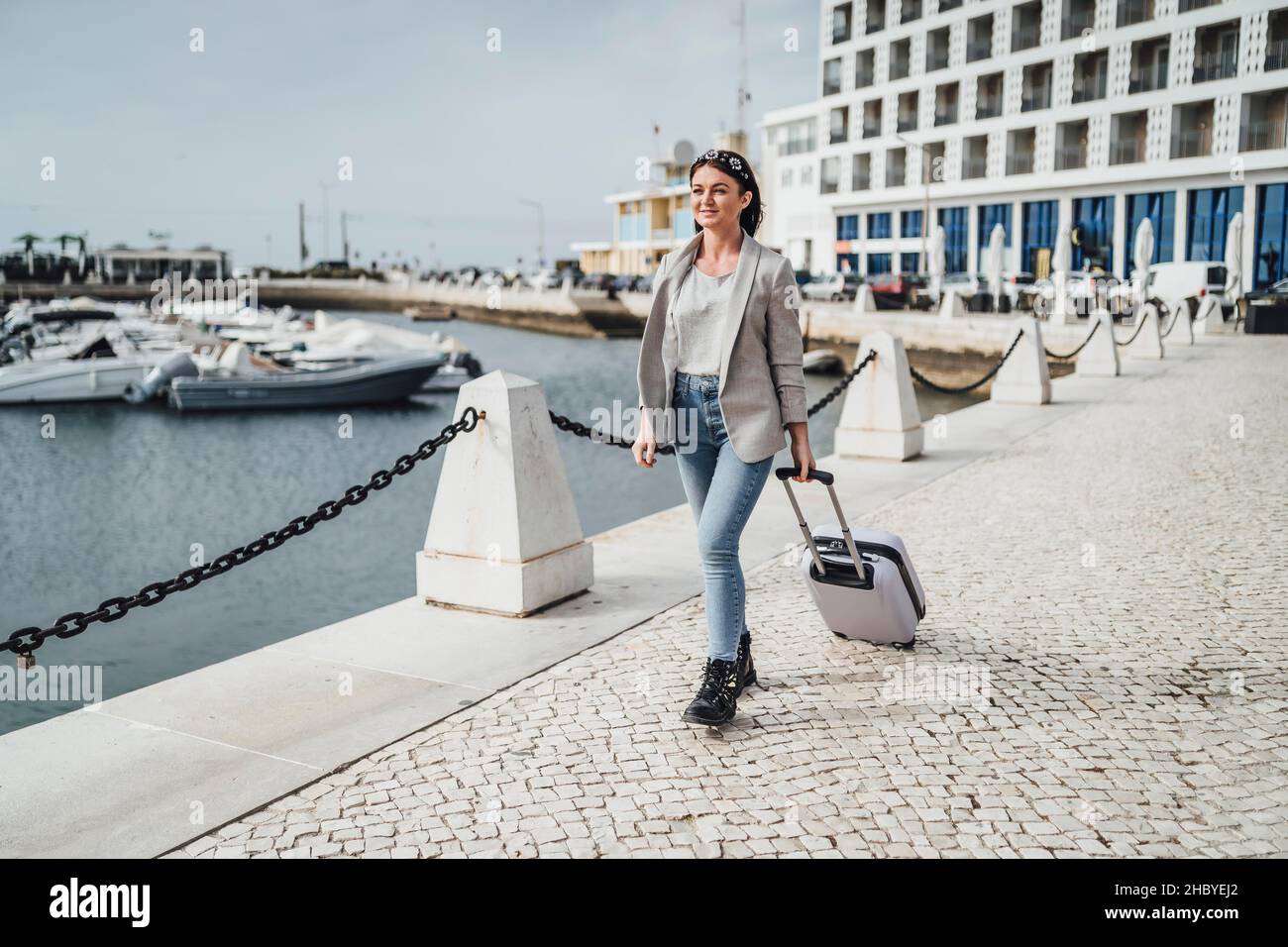 Young woman with suitcase walking in urban settings, Faro, Portugal Stock Photo