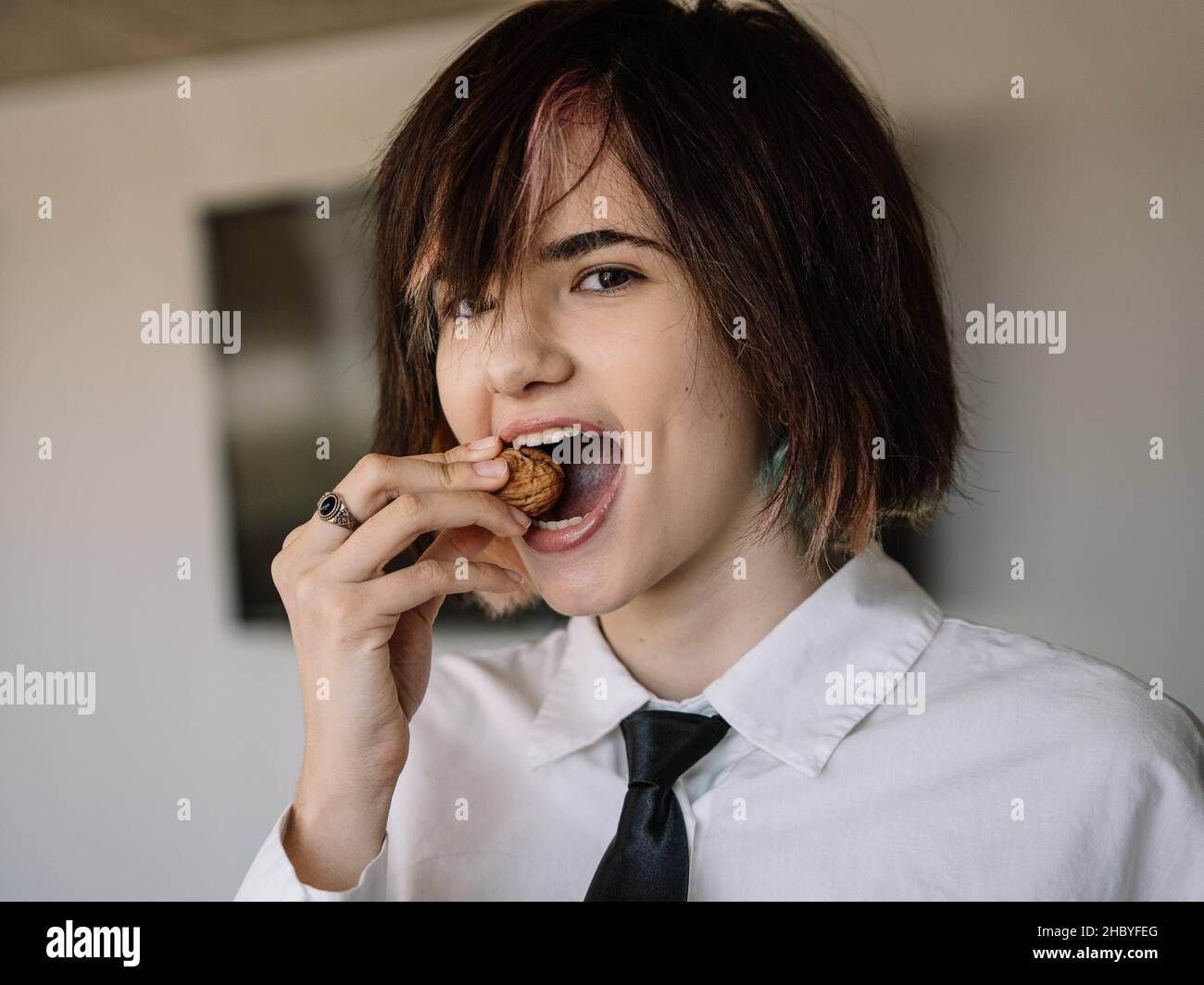 woman looking at the camera while trying to crack a walnut shell with her teeth, horizontal portrait Stock Photo