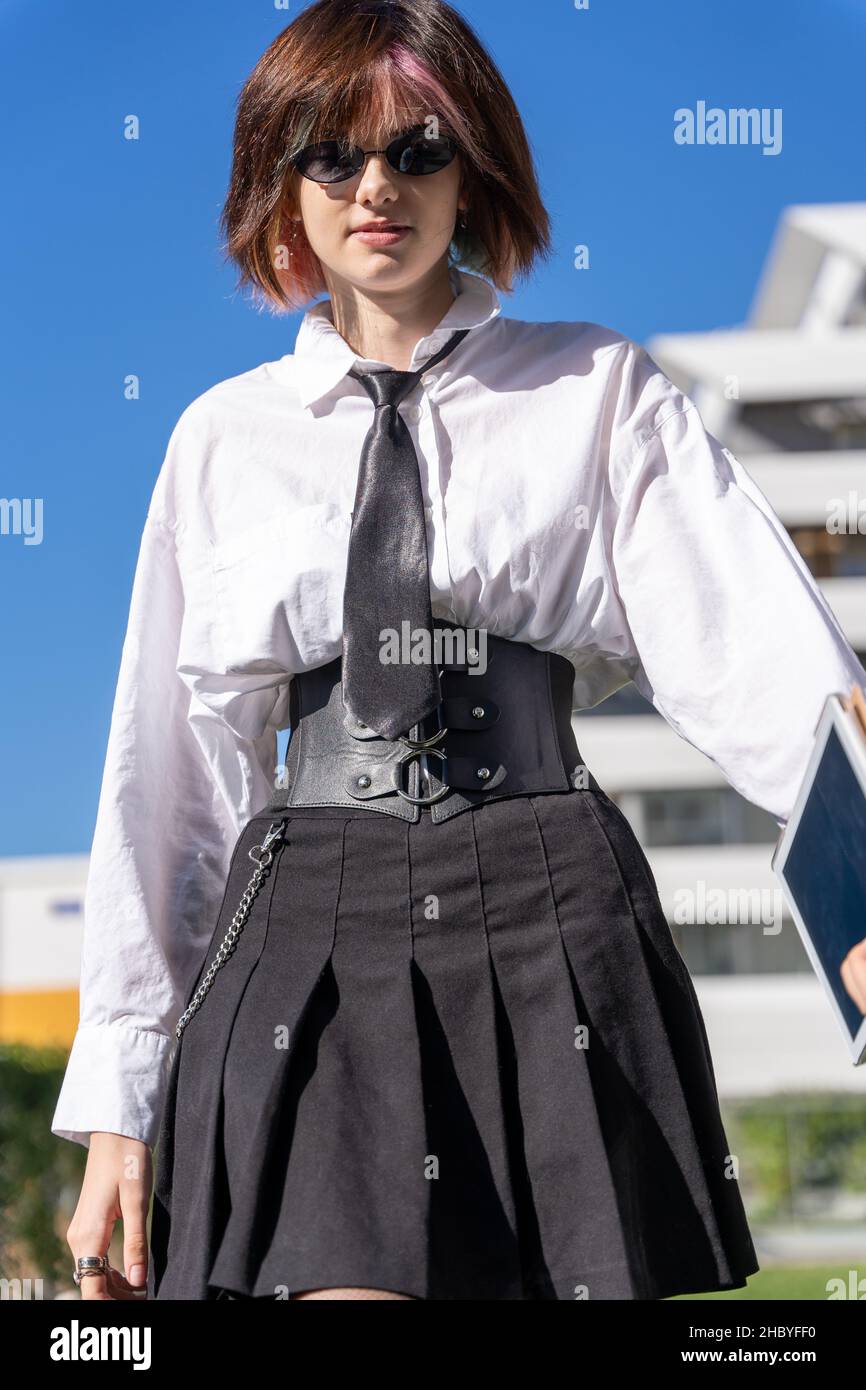 close-up view of woman in shirt, tie and skirt walking forward, vertical portrait, view from below Stock Photo